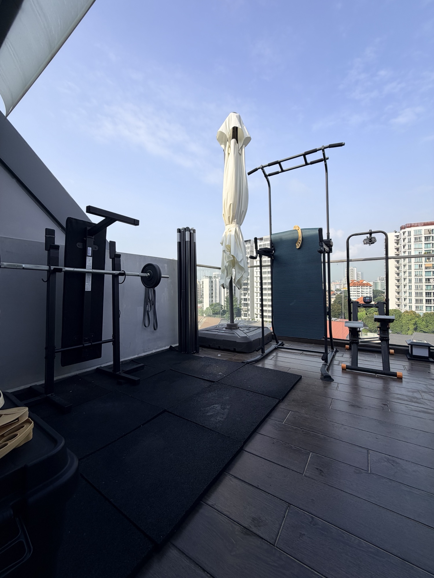 The private rooftop terrace: gym equipment and the cantilever umbrella against the city skyline